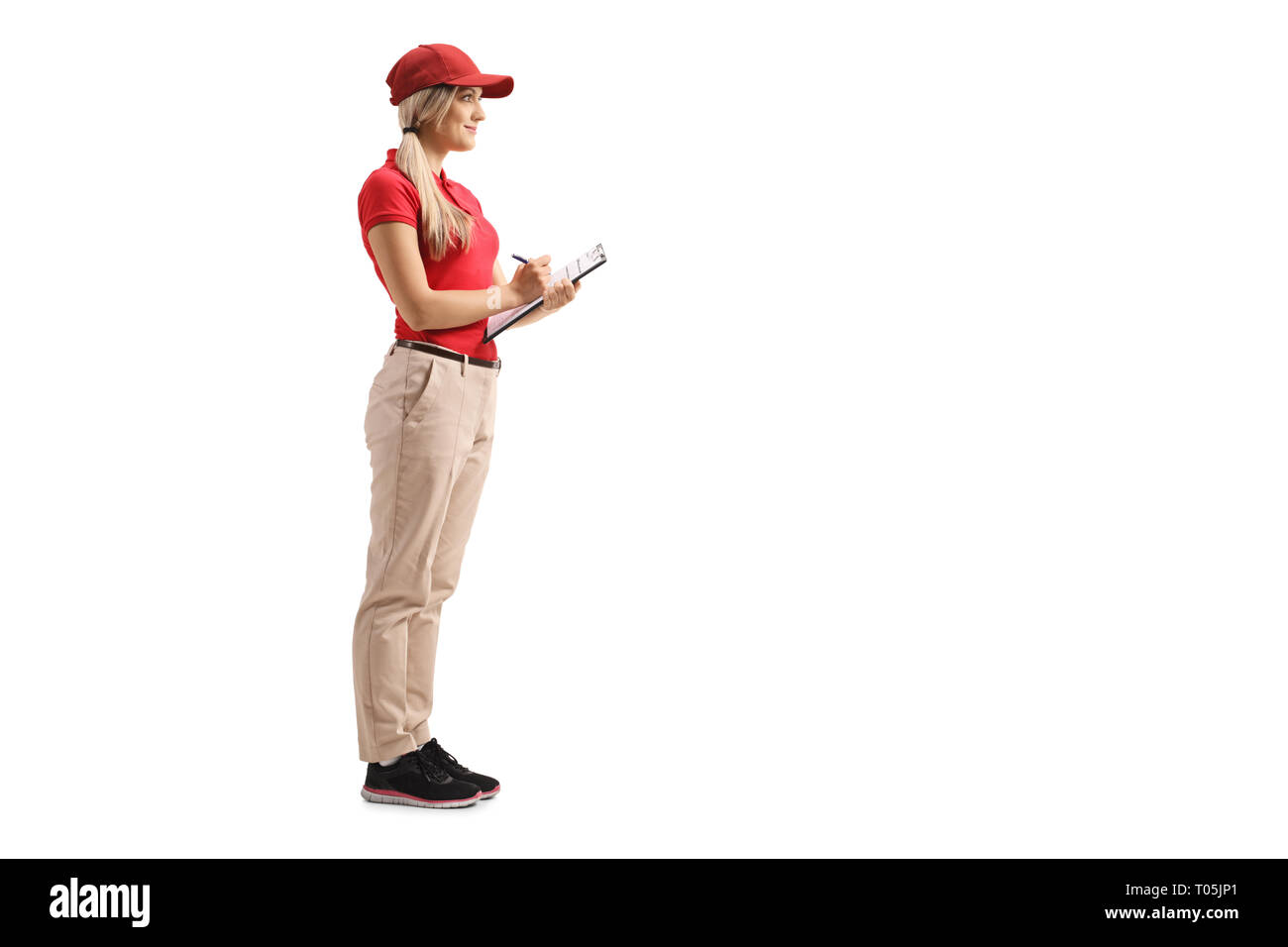 Full length shot of a delivery girl in a red t-shirt standing with a clipboard isolated on white background Stock Photo