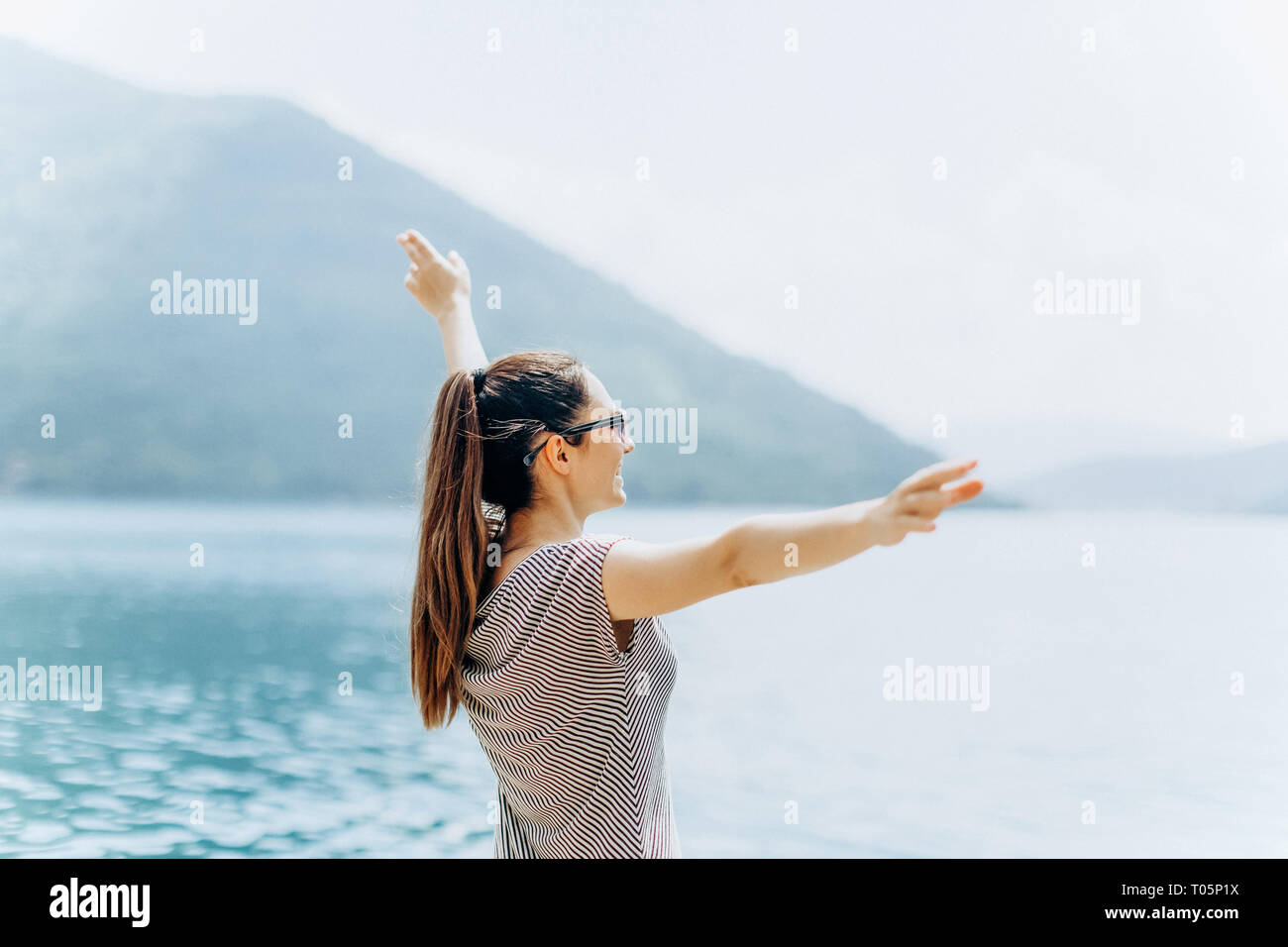 The girl on the background of the sea raises her hands up and shows how ...