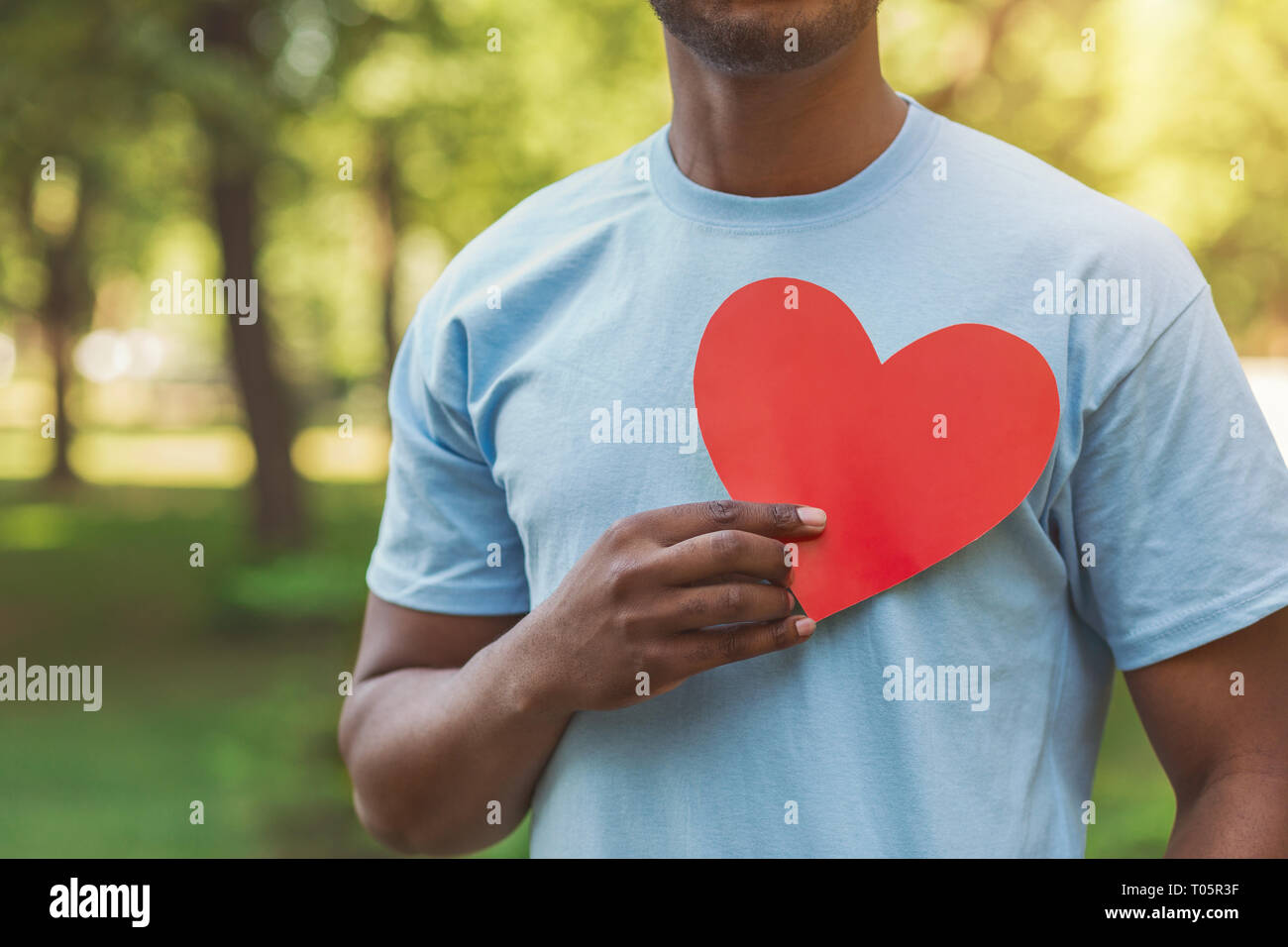 Black man holding red heart on his chest Stock Photo - Alamy