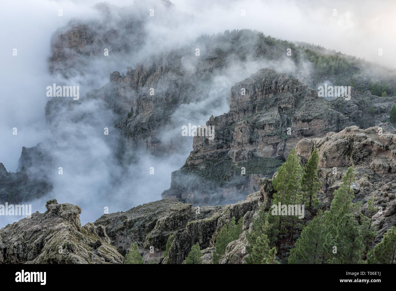 Misty mountain landscape view from eroded stone arch know as Ventana del nublo or La Agujereada. One of the higest places in Gran Canaria Island. Stock Photo