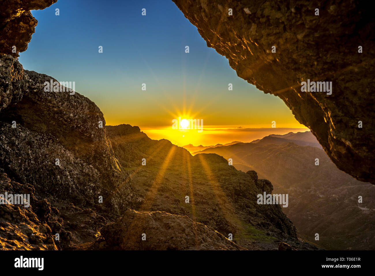 Sunset and mountain landscape view from eroded stone arch know as Ventana del nublo or La Agujereada. One of the higest places in Gran Canaria Island. Stock Photo