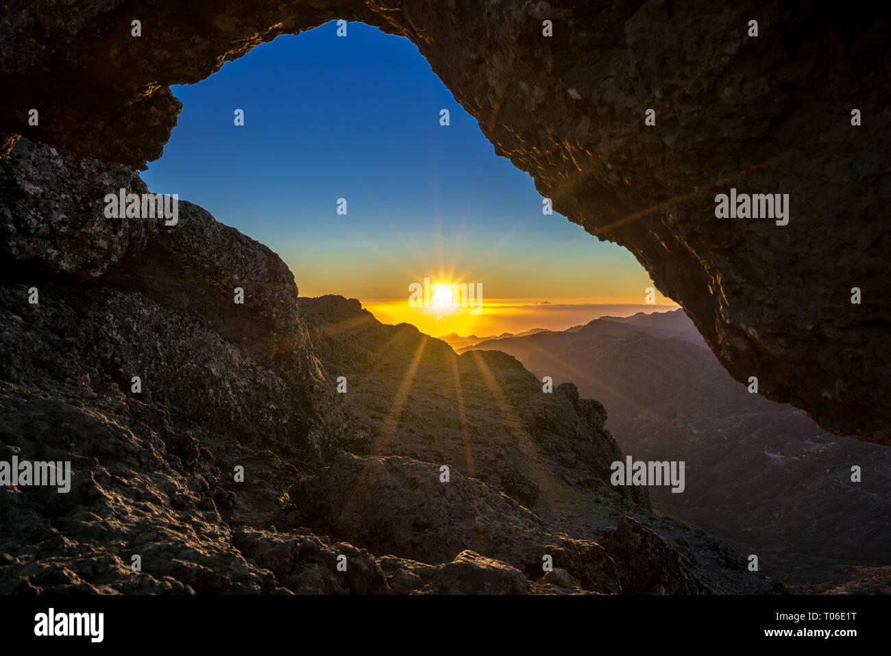 Sunset and mountain landscape view from eroded stone arch know as Ventana del nublo or La Agujereada. One of the higest places in Gran Canaria Island. Stock Photo