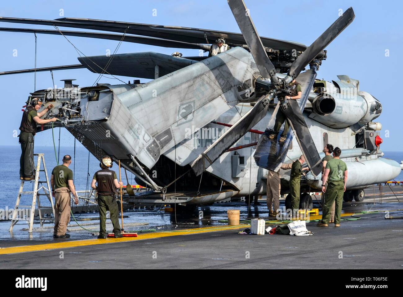 GULF OF OMAN (March 16, 2019) – U.S. Marine pilots and maintenance personnel with the 22nd Marine Expeditionary Unit wash a CH-53E Super Stallion on the flight deck of the Wasp-class amphibious assault ship USS Kearsarge (LHD-3). Marines with Marine Medium Tiltrotor Squadron 264 (Reinforced) performed post exercise wash downs and re-greasing on aircraft in order to maintain operational readiness. Marines and Sailors with the 22nd MEU and Kearsarge Amphibious Ready Group are currently deployed to the U.S. 5th Fleet area of operations in support of naval operations to ensure maritime stability a Stock Photo