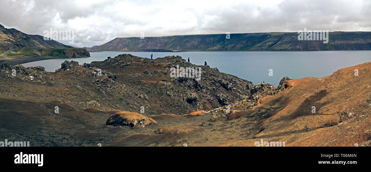 an Inland Lake and coastline roads in the volcanic landscape of central Iceland. A barren rugged lake shore is filled with volcanic rocks. Stock Photo