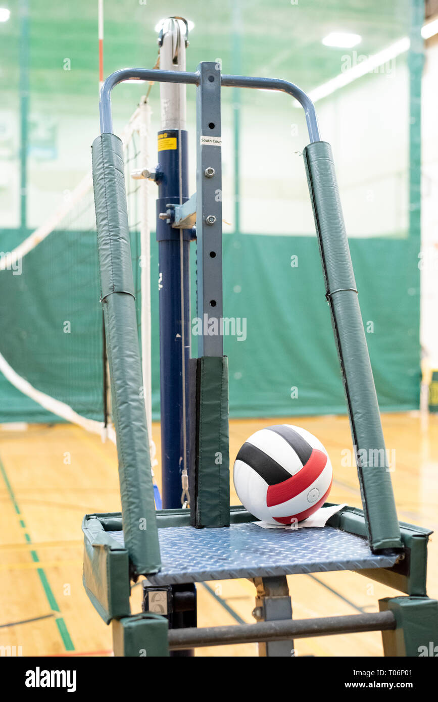 Red, black, and white volleyball and net in a school gymnasium