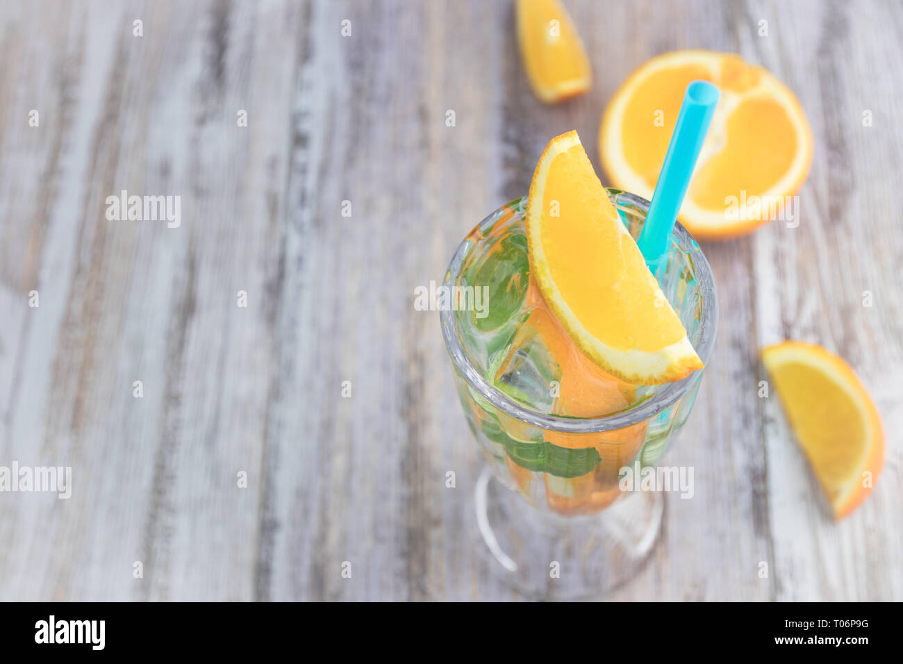 Citrus refreshing drink in a glass goblet on a wooden table. summer refreshing cocktail. Healthy food, drinks. orange and mint ice water. Copy space Stock Photo