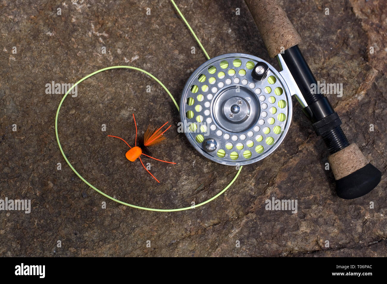Fly fishing Rod and Reel with Orange Spider Lure on Wet Rocks Stock Photo -  Alamy