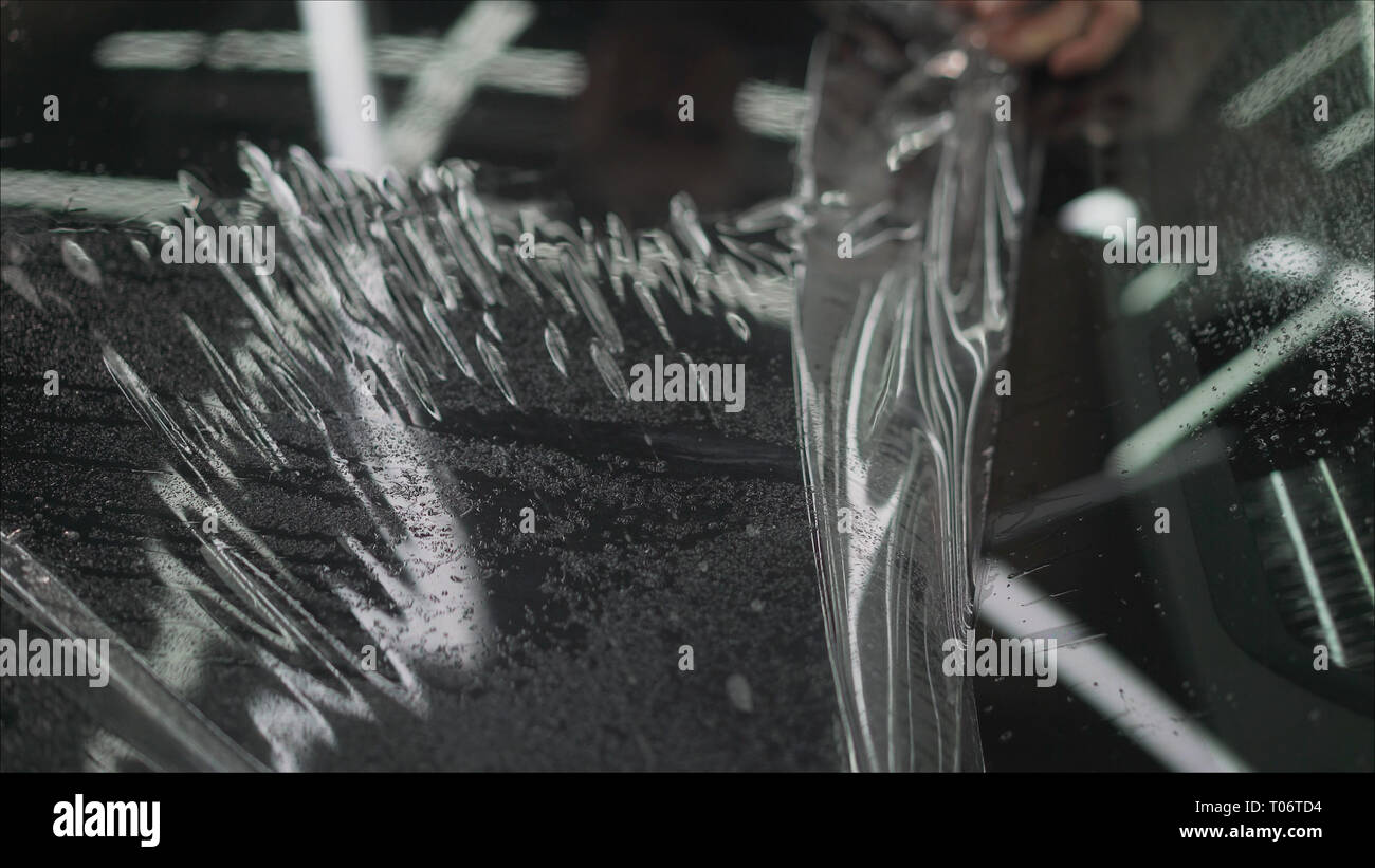 professional applying protective film to the red car. Master glues a