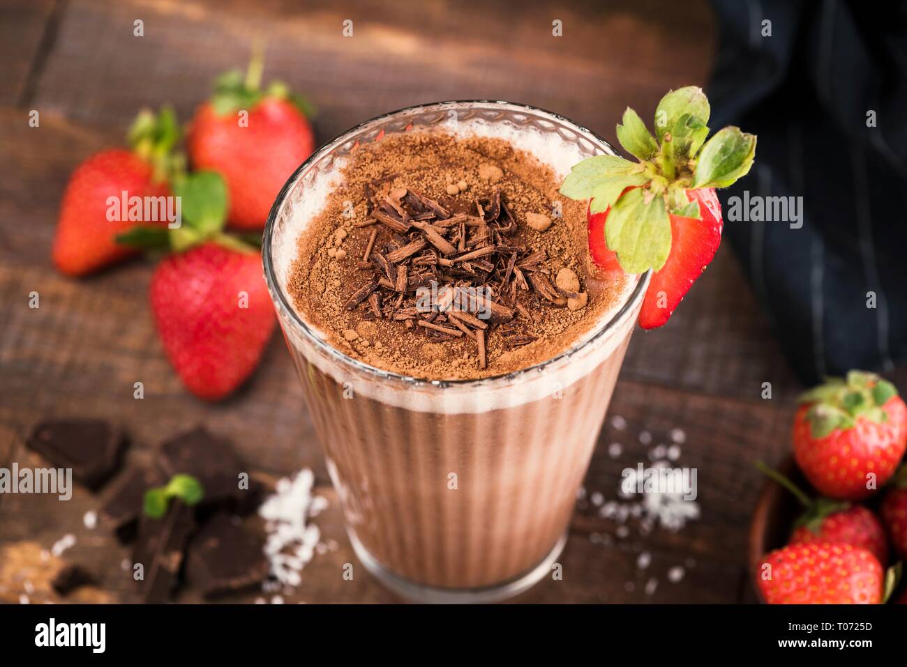 Strawberry Chocolate Milkshake With Chocolate Shavings, Cocoa In Tall Glass On Wooden Background. Closeup view, Selective focus Stock Photo