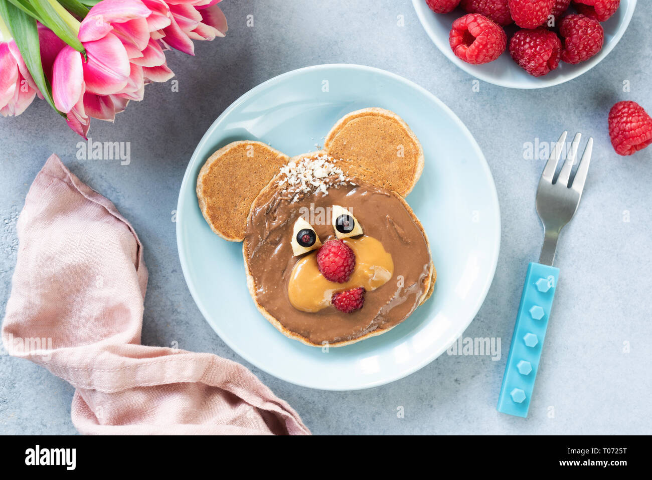 Cute bear shape pancake with nut butter for kids healthy breakfast. Creative kids food idea, food art. Top view. Stock Photo