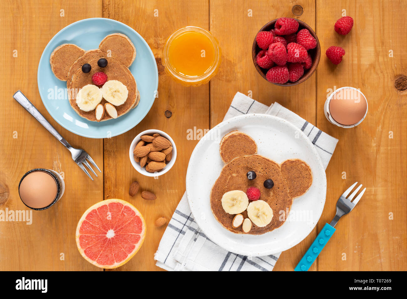 Funny pancakes foor art for kids. Healthy breakfast Table top view on a wooden table. Walrus, dog or bear shaped pancakes decorated with fruits and be Stock Photo