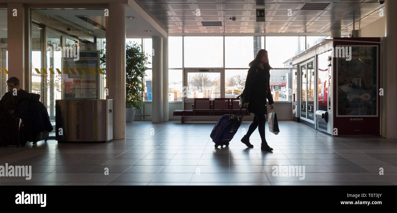 Traveller walking with a luggage trolley in an airport, Bologna airport