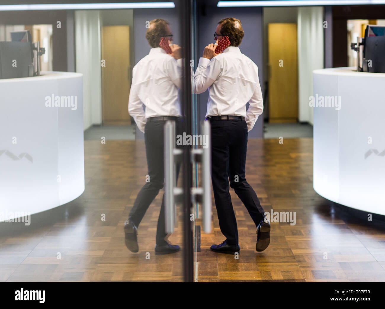 Frankfurt, Germany. 18th Mar 2019. A man makes a telephone call in the trading room of the stock exchange and is reflected in a glass wall (l). Photo: Frank Rumpenhorst/dpa Credit: dpa picture alliance/Alamy Live News Stock Photo