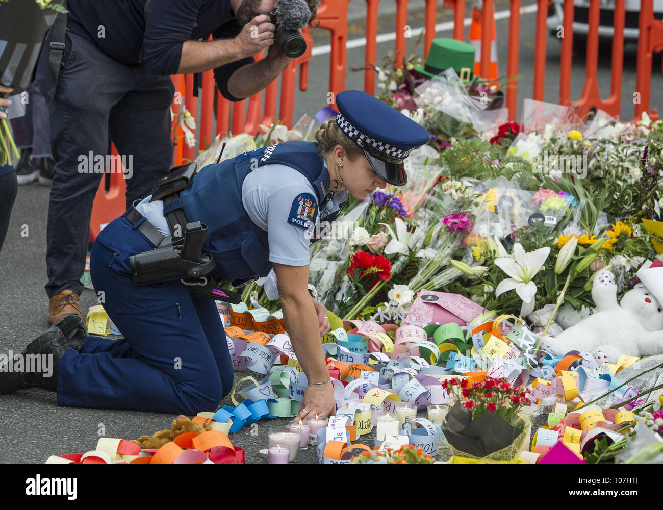 Christchurch, Canterbury, New Zealand. 18th Mar, 2019. A police officer helps arrange tributes following a ''Students' Uniting in Love'' vigil in Hagley Park, near the Al Noor mosque, where 41 people were killed. Thousands of local school students attended the vigil, organized by Cashmere High School students, where several current and former pupils were killed or wounded in two city mosque shooting that left at least 50 people dead. Credit: PJ Heller/ZUMA Wire/Alamy Live News Stock Photo