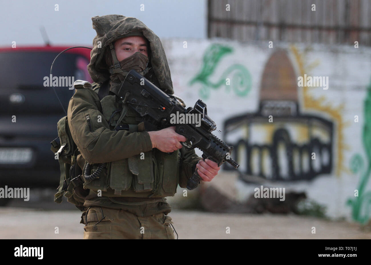 Nablus, West Bank city of Nablus. 18th Mar, 2019. An Israeli soldier patrols a street in Salem village, east of the West Bank city of Nablus, March 18, 2019. Israeli troops searched the West Bank for the suspected Palestinian killer of an Israeli soldier on Monday. The Palestinian killed an Israeli and severely injured two others in shooting and stabbing attacks before fleeing the scene on Sunday, Israeli army said. Credit: Nidal Eshtayeh/Xinhua/Alamy Live News Stock Photo