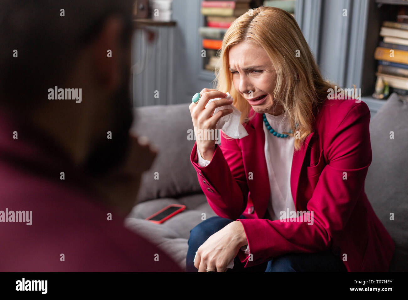 Blonde woman wearing accessories crying visiting therapist Stock Photo