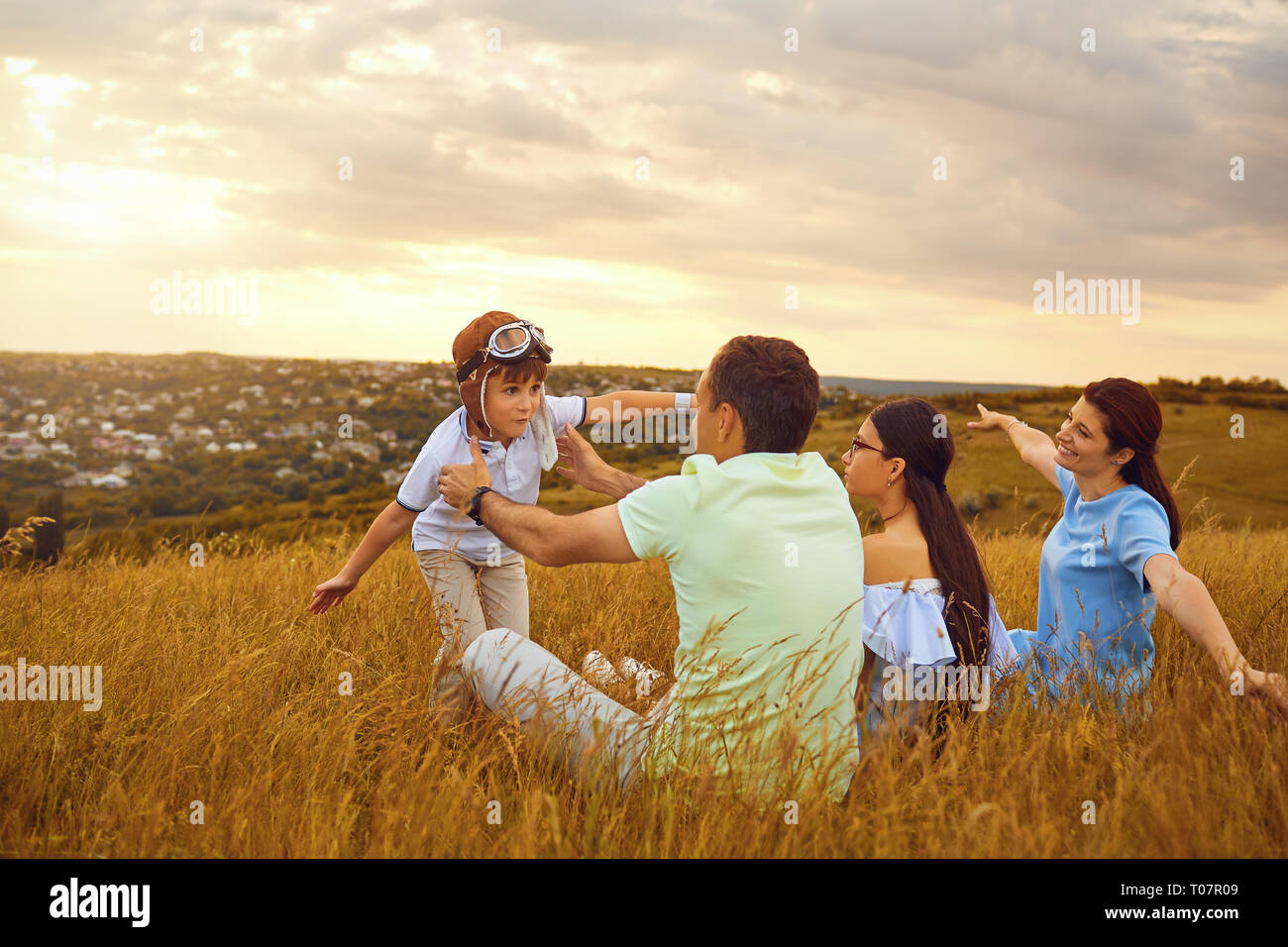 Happy family playing on grass in nature at sunset Stock Photo