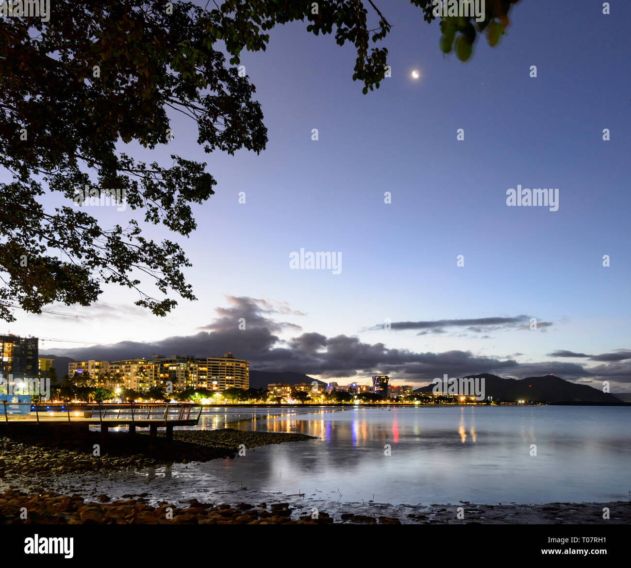 Scenic view of the city of Cairns at nighttime with the bay illuminated and the moon visible, Far North Queensland, FNQ, QLD, Australia Stock Photo