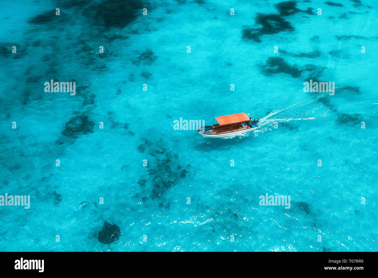 Aerial view of the fishing boat in transparent blue water at sunny day ...
