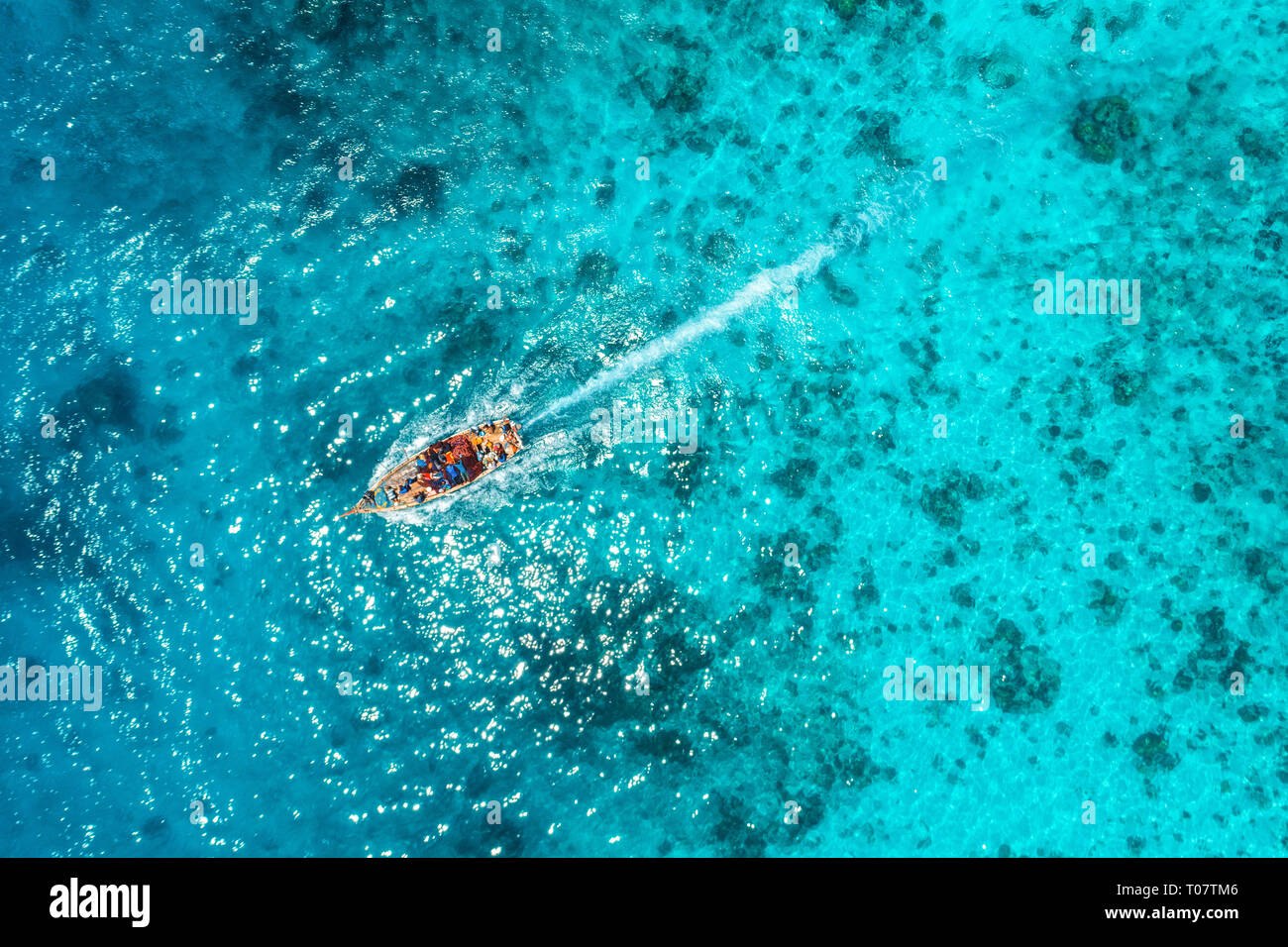 Aerial view of the fishing boat in transparent blue water at sunny day ...