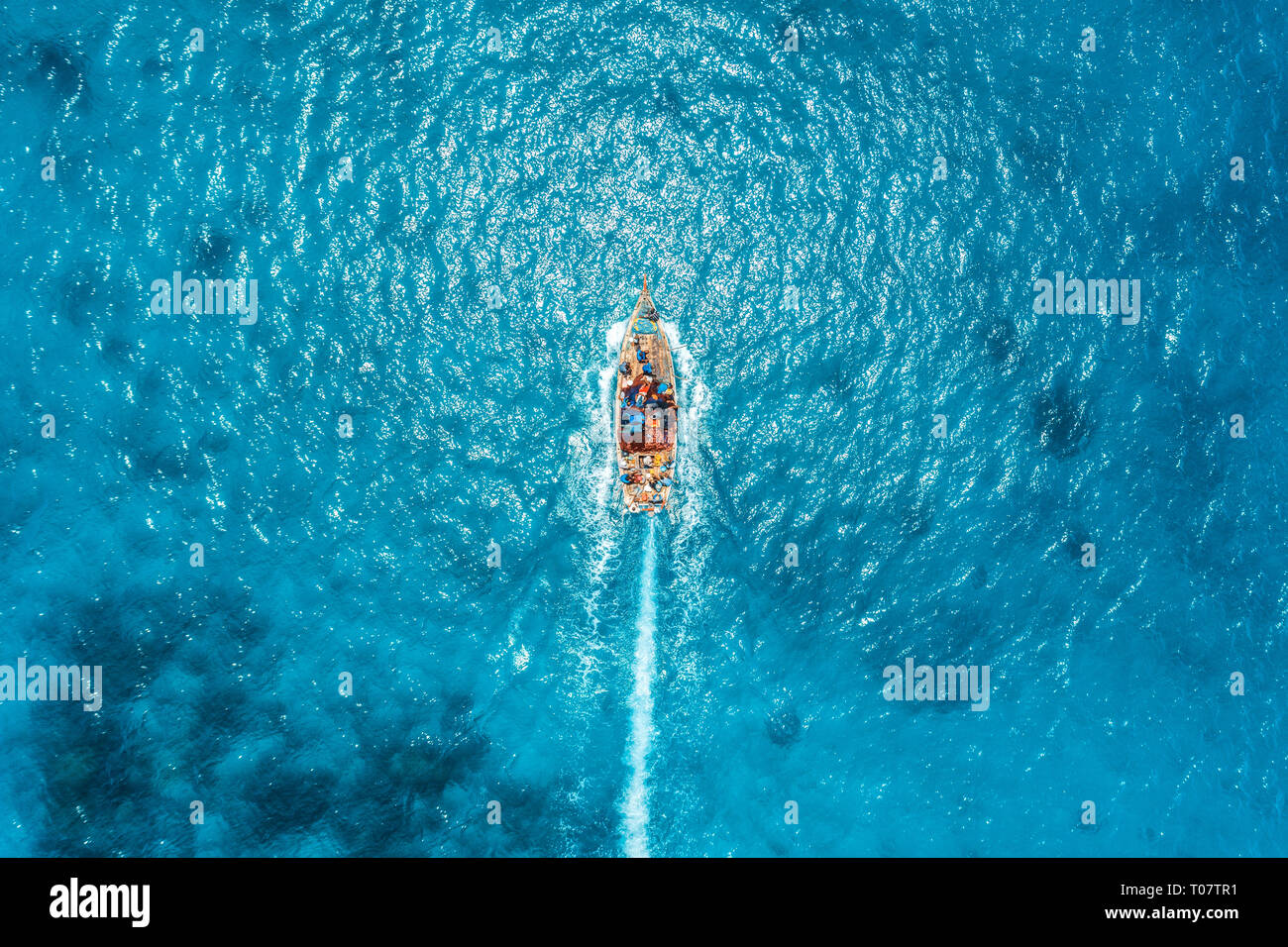 Aerial view of the fishing boat in transparent blue water at sunny day ...