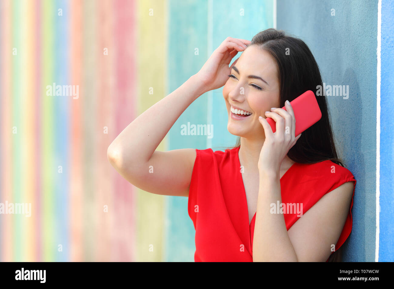 Candid fashion woman in red talking on smart phone in a colorful street Stock Photo
