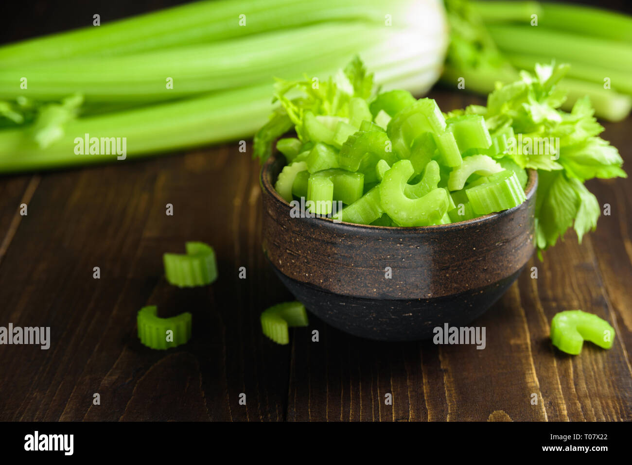 Cutted celery sticks in ceramic bowl on wooden background Stock Photo