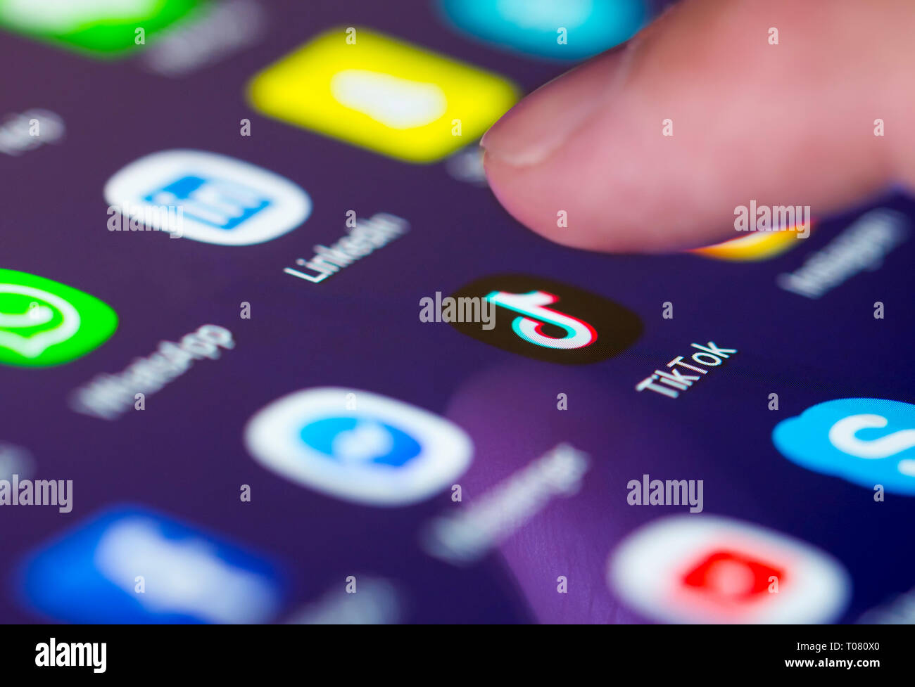 Finger pressing TikTok app icon (AKA Douyin) on a touchscreen on a tablet or mobile phone device. Loading Tik Tok application. TikTok shortcut. Stock Photo