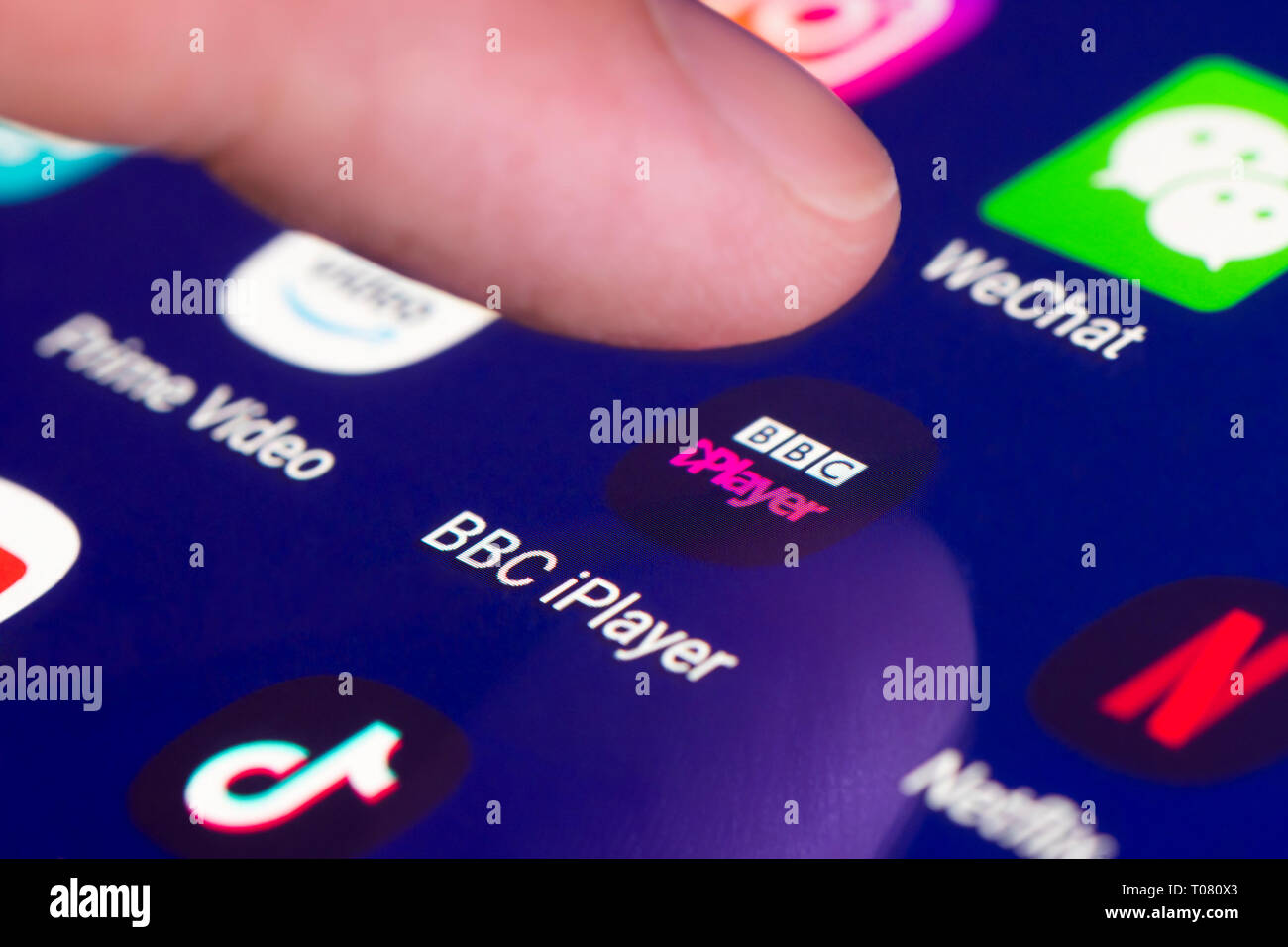 Finger pressing BBC iPlayer app icon on a touchscreen on a tablet or mobile phone device. Loading BBC iPlayer application. BBC iPlayer ]Shortcut. Stock Photo