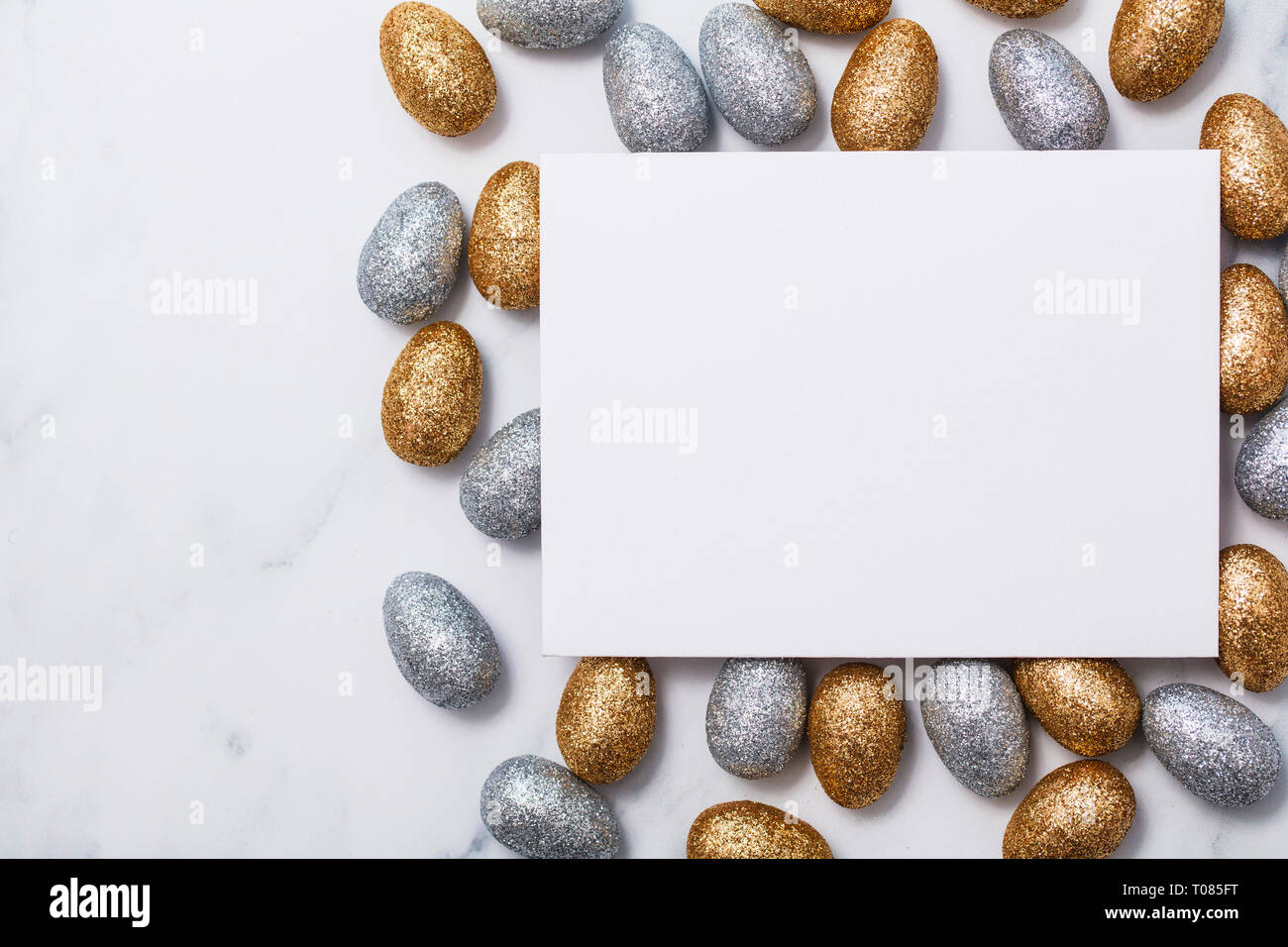 Easter background with a blank white card and glitter easter eggs Stock Photo