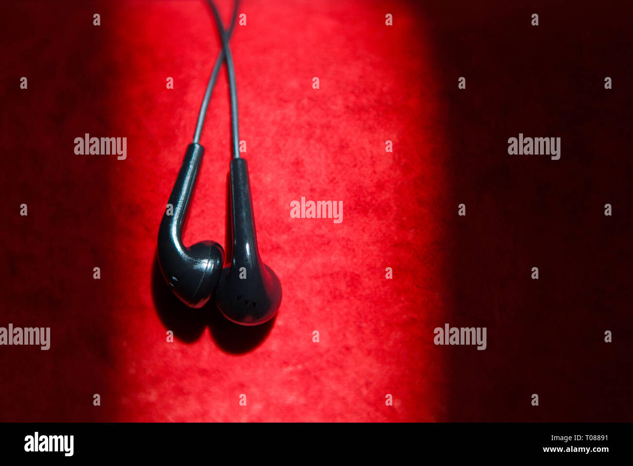 Top view of black earphones on a red velvet texture background. concept lifestyle. hight contrast colors. Stock Photo