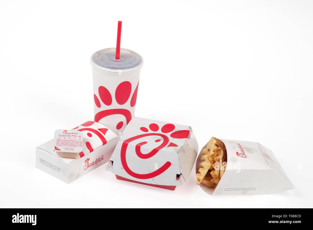 Chick-Fil A fast food takeout packages including a sandwich box, chicken nuggets box, waffle fries packet and soda Stock Photo