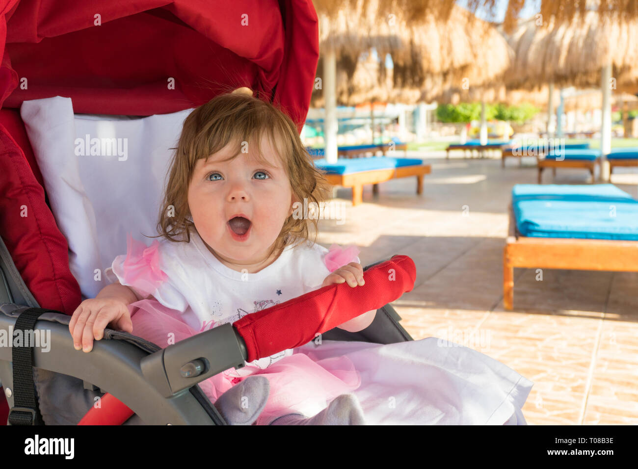 Funny surprised baby girl in carriage on resort Stock Photo