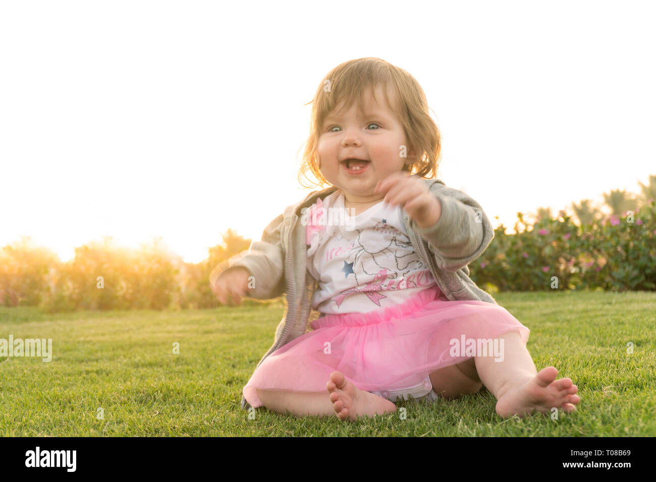 Funny smiling happy girl sitting on grass Stock Photo - Alamy