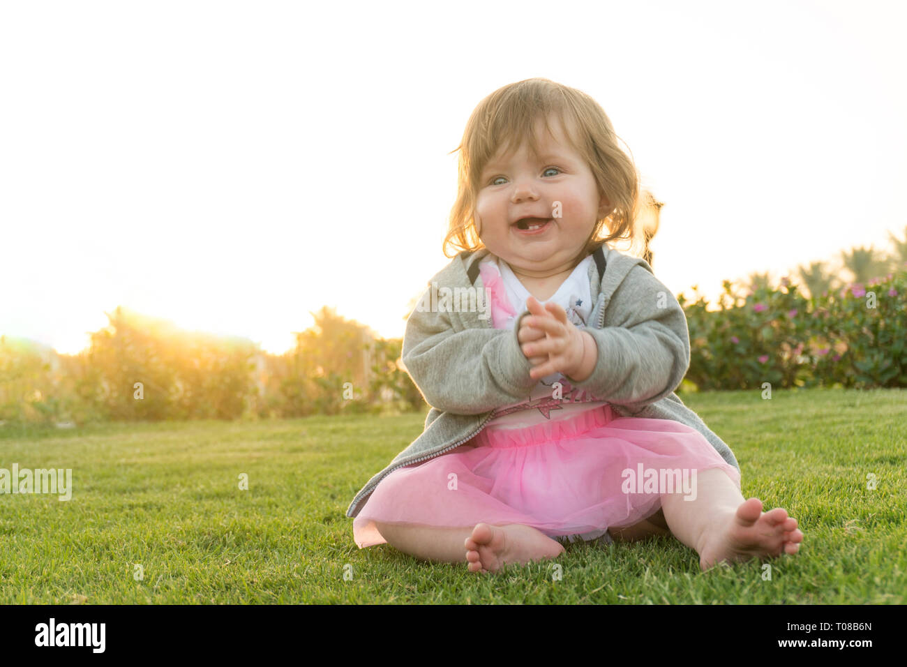 Little funny baby girl sitting on the grass Stock Photo