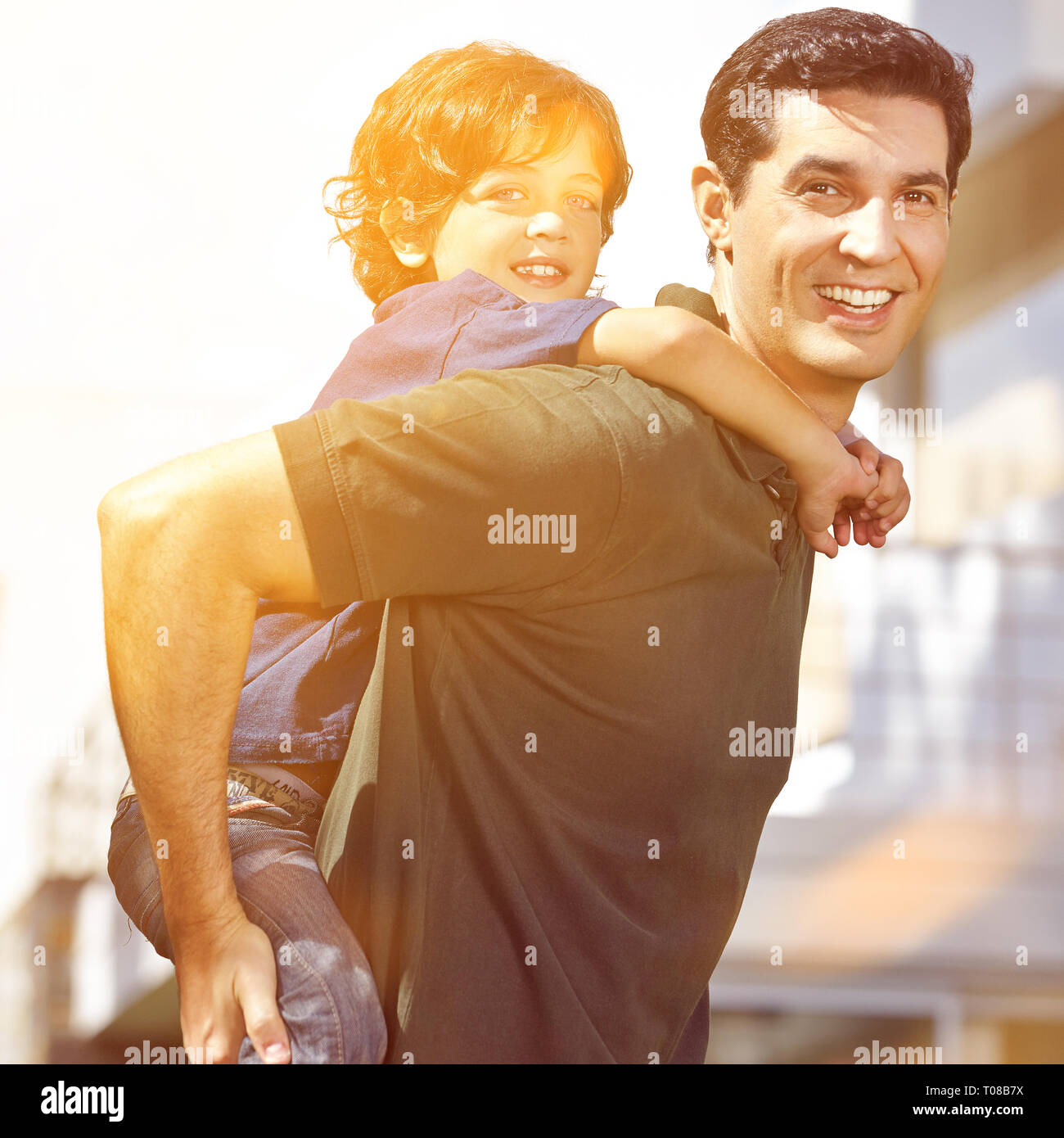 Father carries his son piggyback on his back in the garden Stock Photo