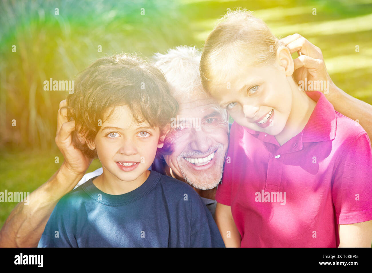 Happy grandfather with his two grandchildren in the garden Stock Photo