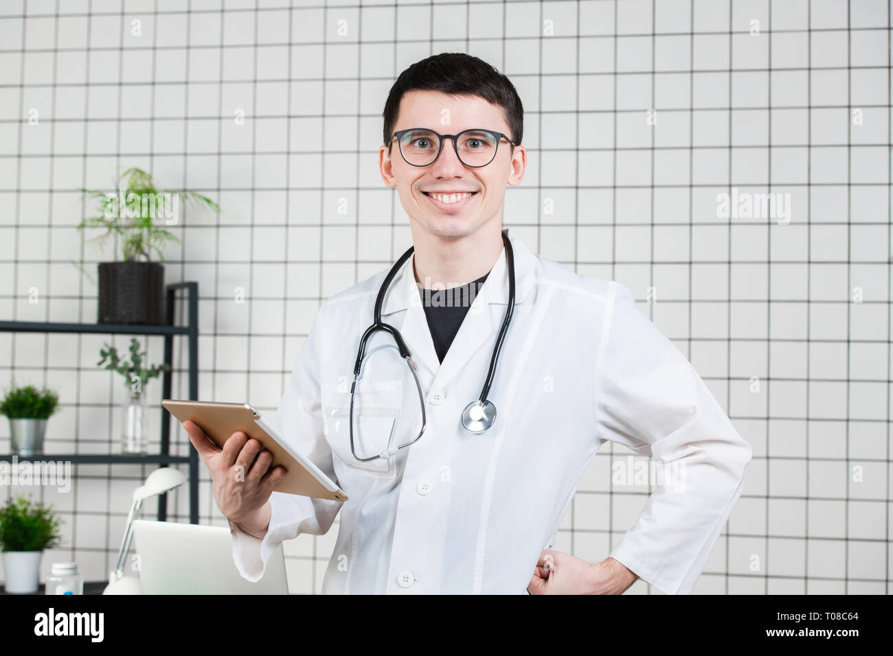 Smiling handsome young male doctor using tablet computer. Technologies in medicine concept Stock Photo