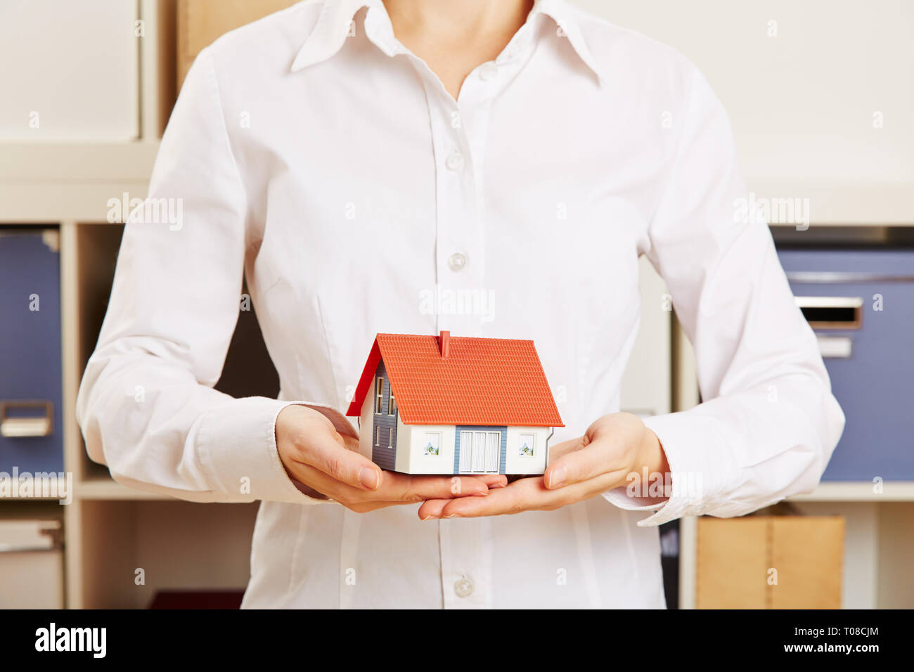 Hands of a woman hold a small house as a concept for mortgage lending Stock Photo