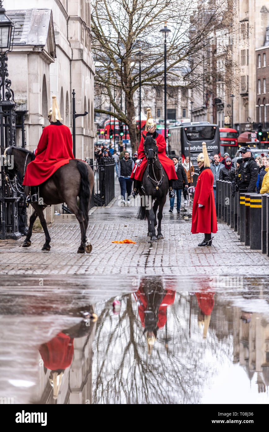 Changing of the Guard mounted ceremony after heavy rain. Reflected in puddle. Life Guards of the Household Cavalry in winter uniform long coats Stock Photo