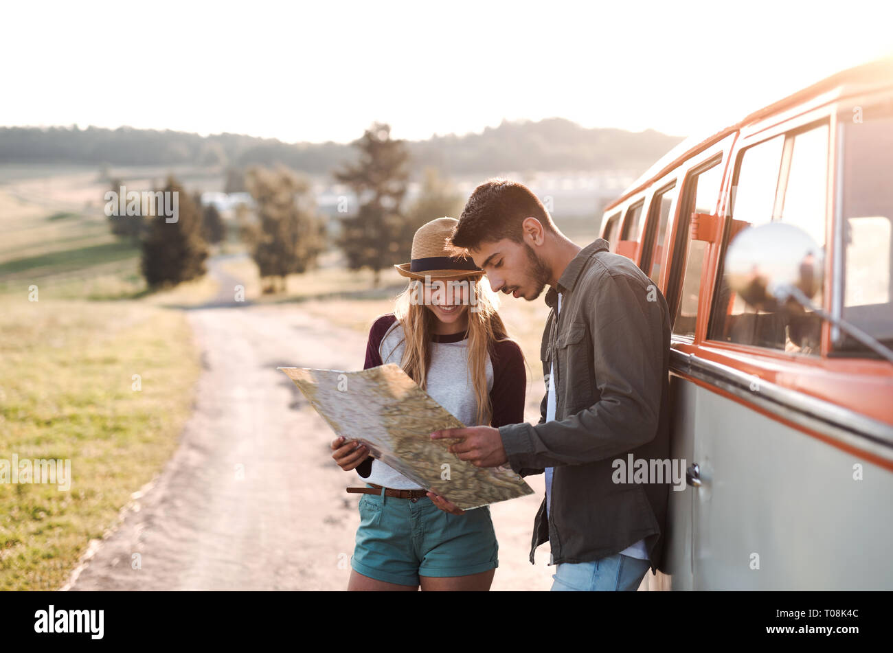 A Young Couple On A Roadtrip Through Countryside Looking At A Map a-young-couple-on-a-roadtrip-through-countryside-looking-at-a-map