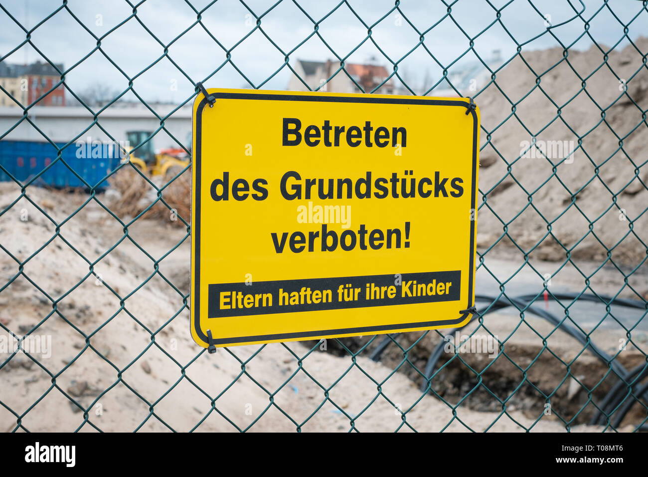Betreten des Grundstücks verboten ! Eltern haften für ihre Kinder ! gelbes Schild an Zaun von Baustelle. Stock Photo