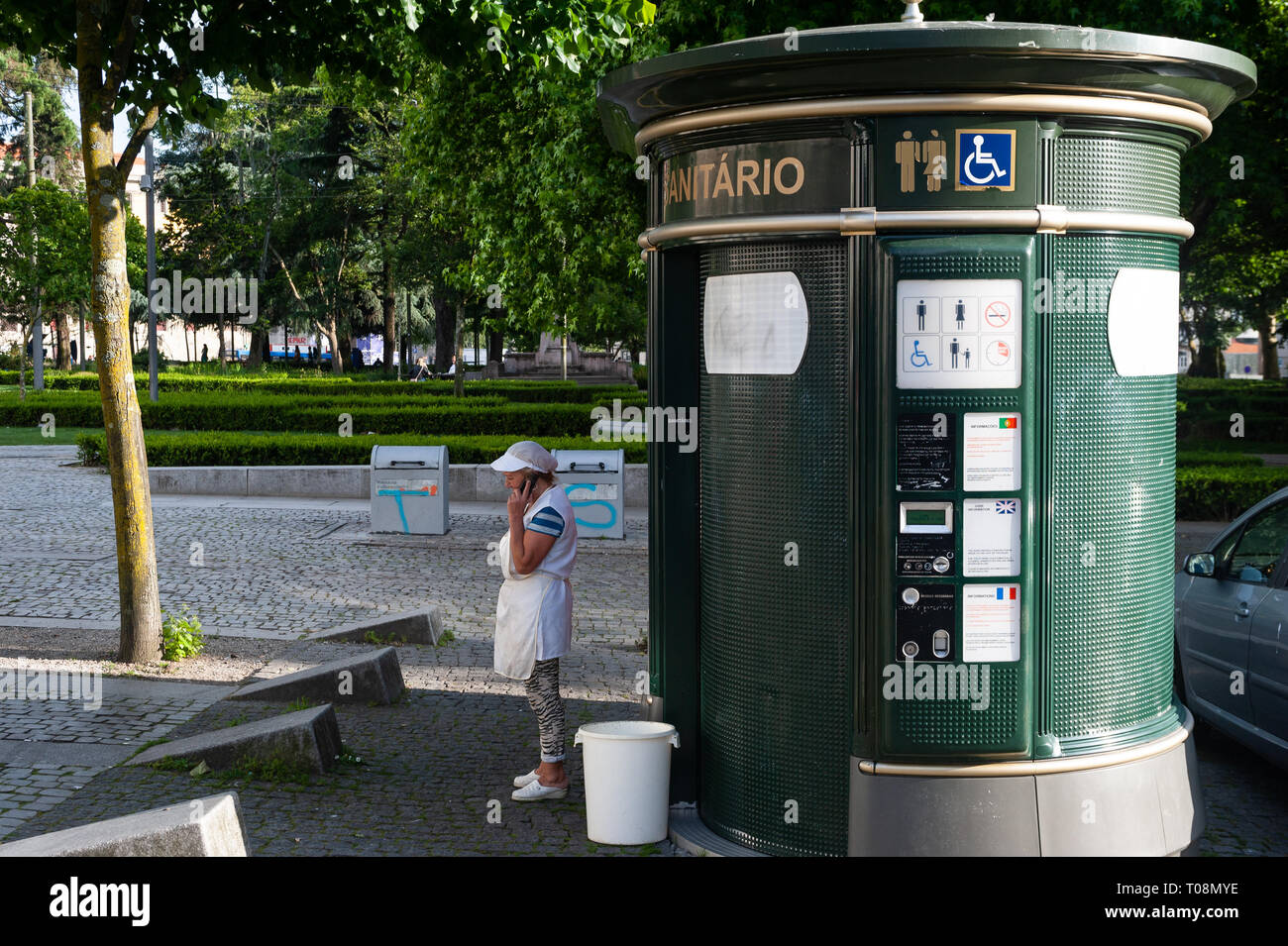 13.06.2018, Porto, Norte, Portugal - A cleaner is on the phone in front of a public toilet in the Altsatdt of Porto. 0SL180613D015CAROEX.JPG [MODEL RE Stock Photo