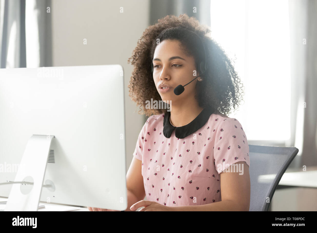African call center operator in wireless headset talking using computer Stock Photo