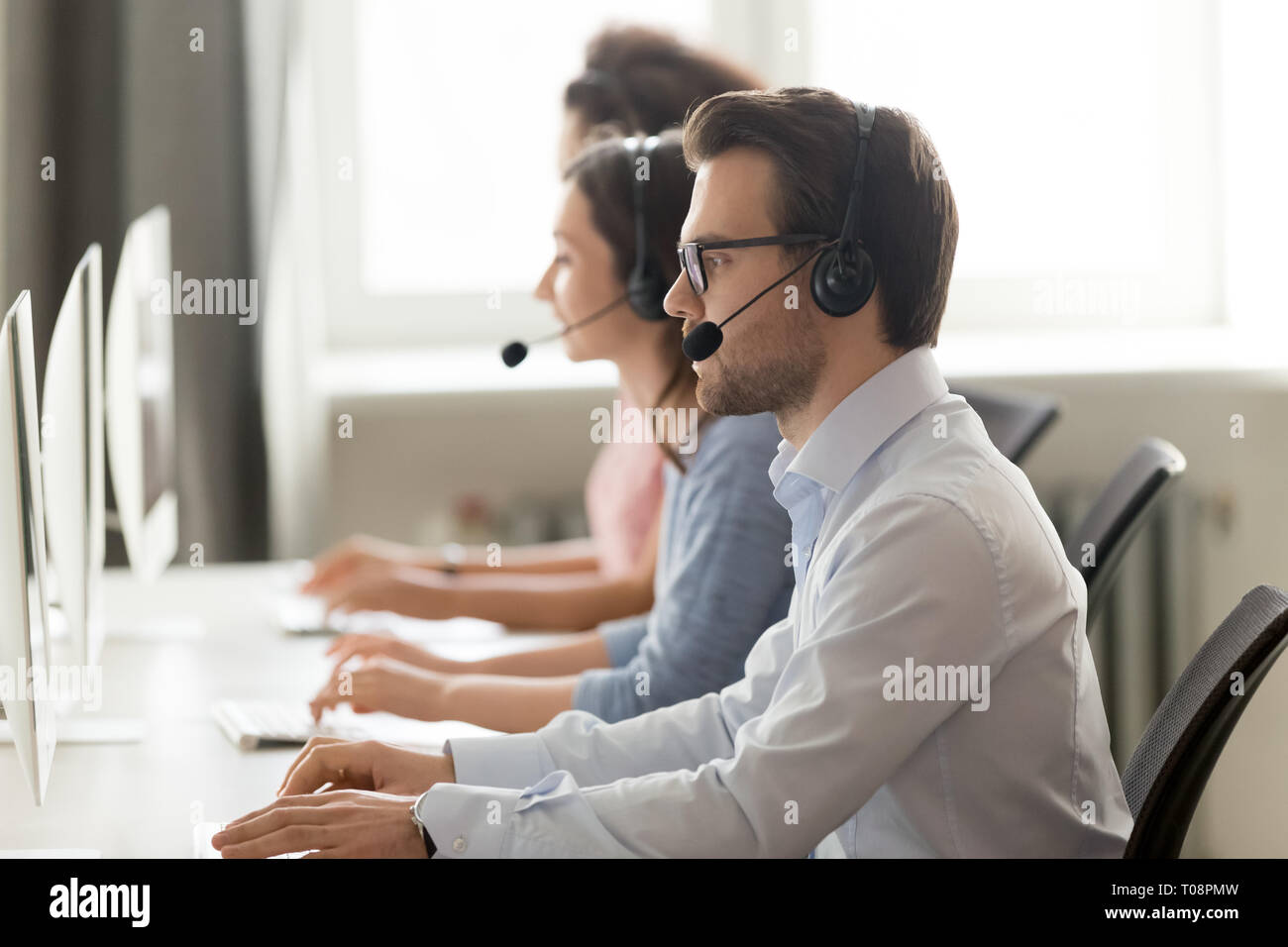 Male call center agent in wireless headset consulting online client Stock Photo