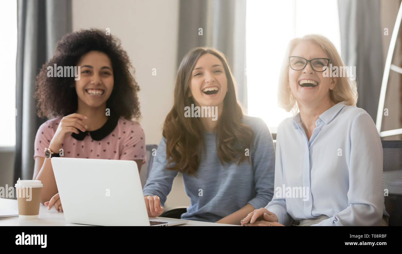Diverse happy young and old busineswomen laughing engaged in meeting Stock Photo