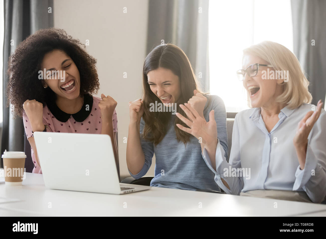 Diverse happy overjoyed female employees team excited by online win Stock Photo