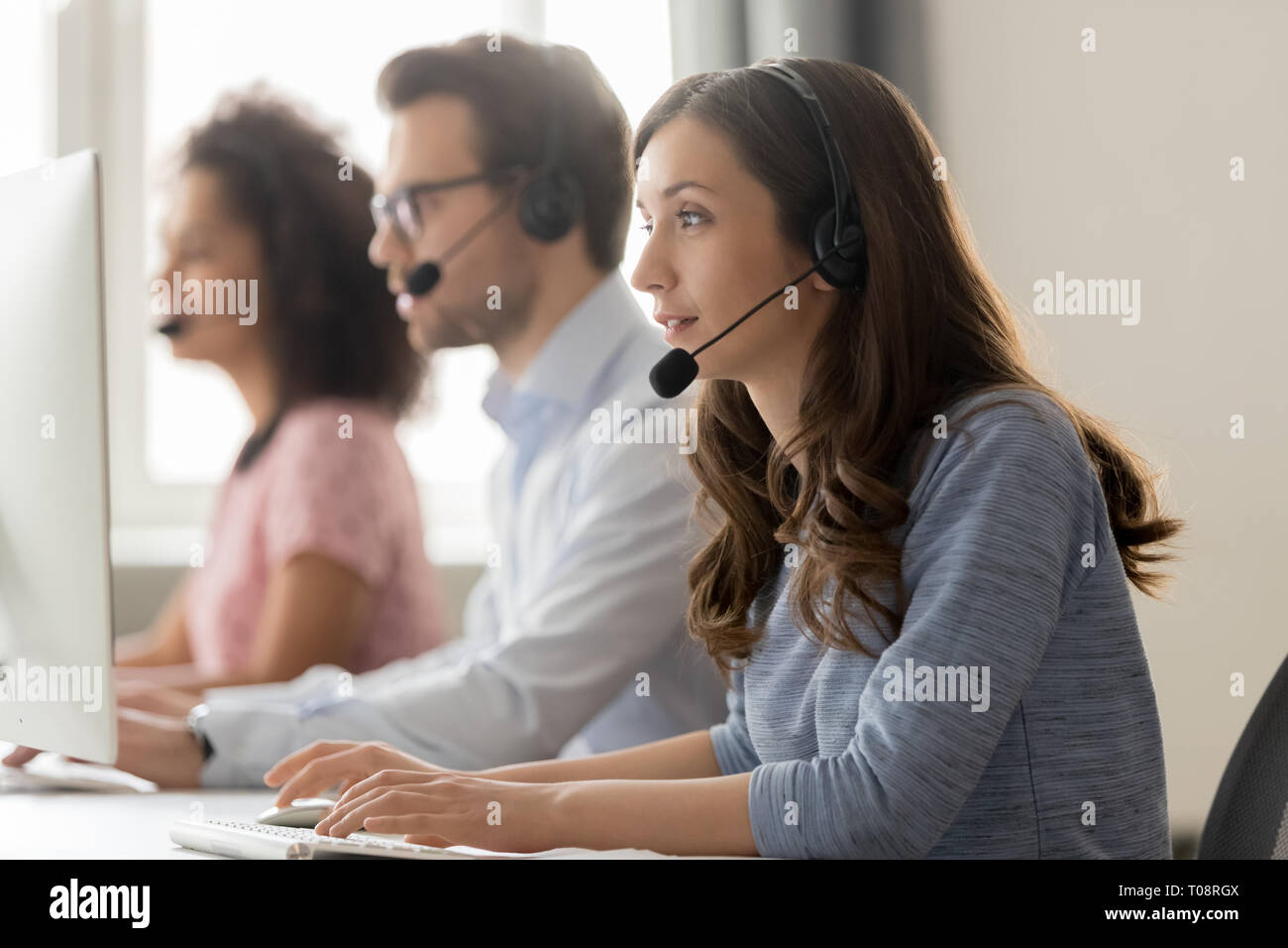 Young woman call center agent in headset consulting online client Stock Photo