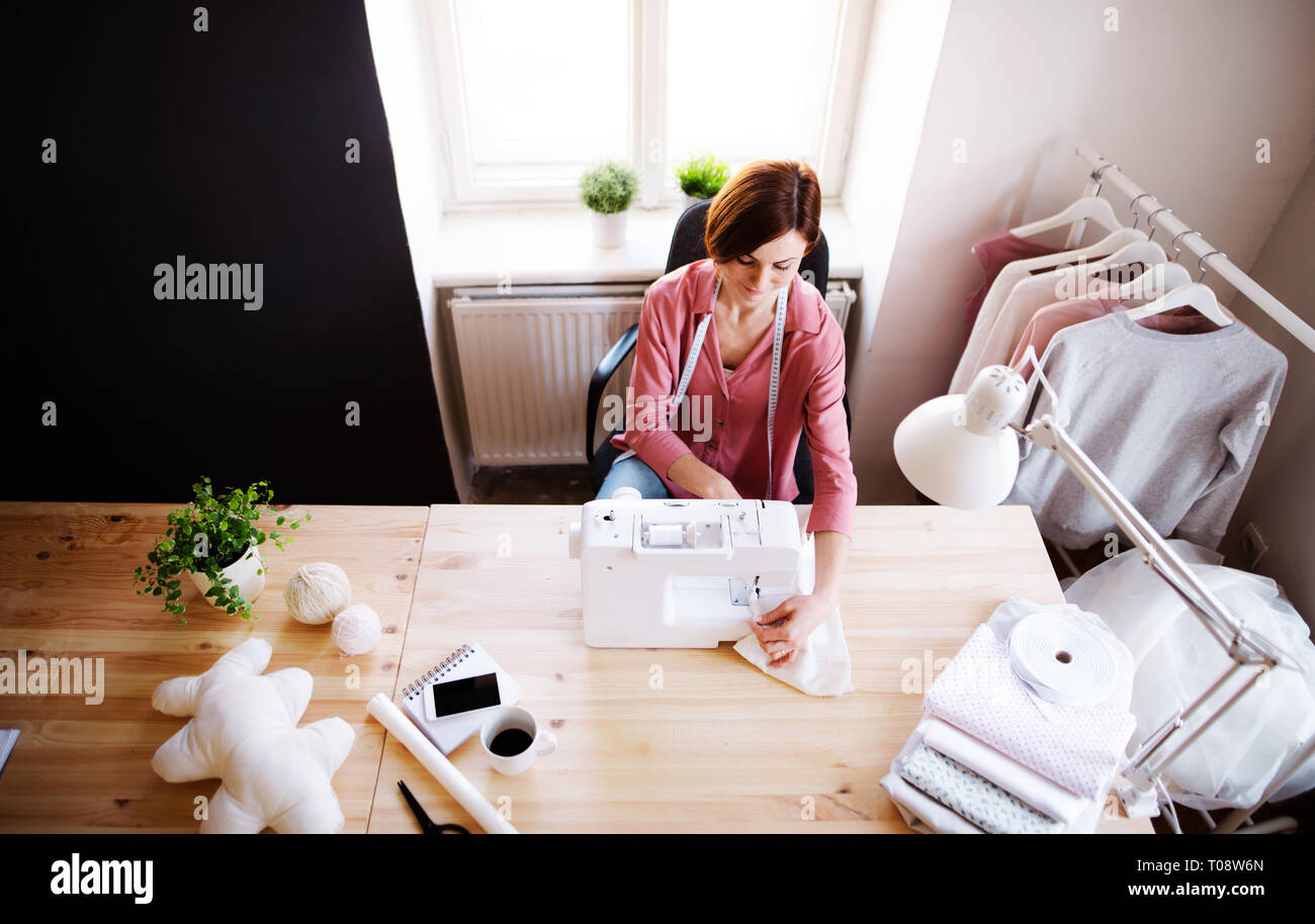 Young creative woman in a studio, working. A startup of tailoring business. Stock Photo