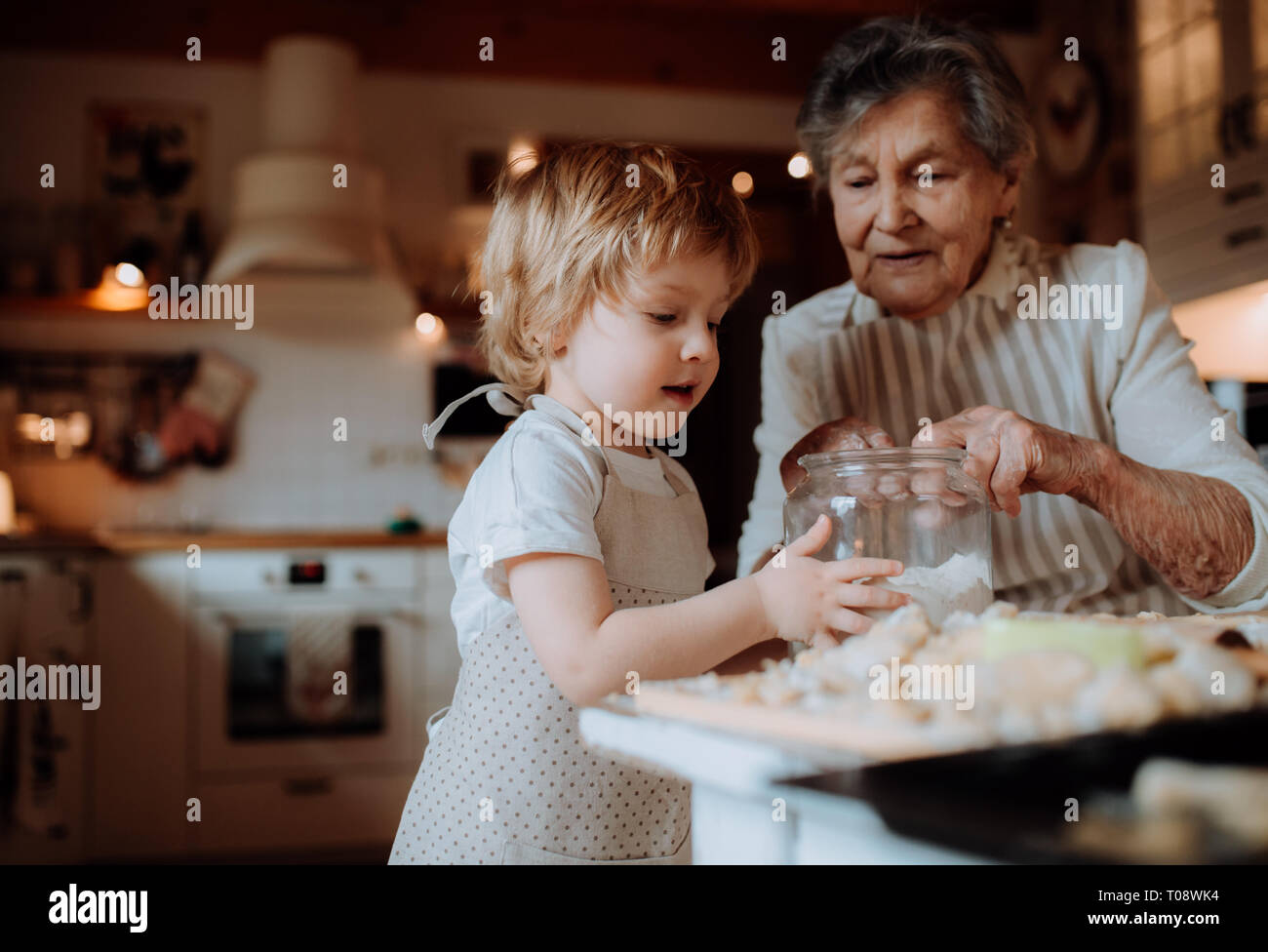 Senior grandmother with small toddler boy making cakes at home. Stock Photo